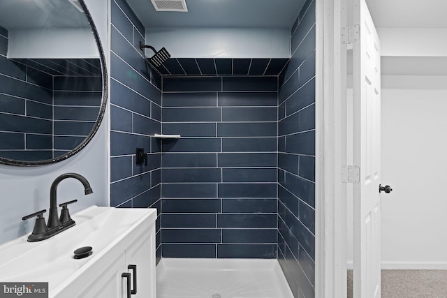 full bath featuring a tile shower, a sink, and visible vents