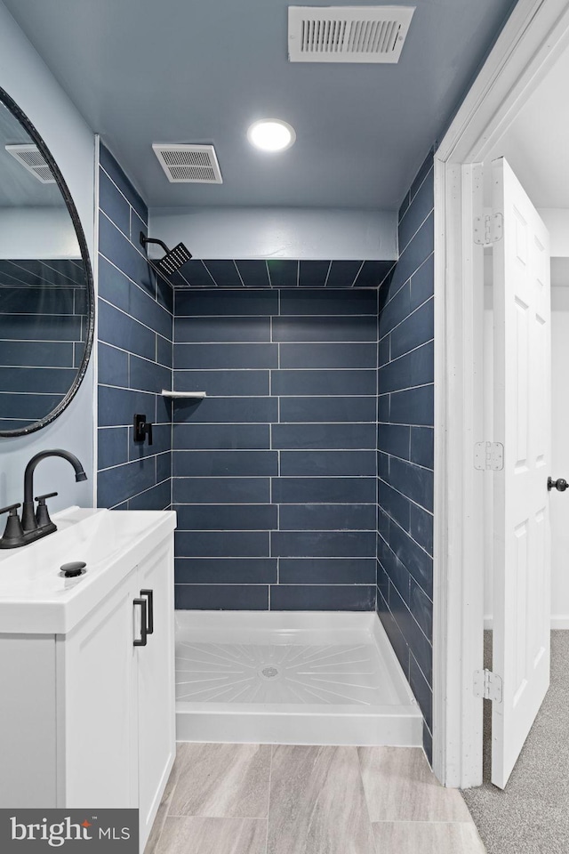 bathroom featuring tiled shower, vanity, and visible vents