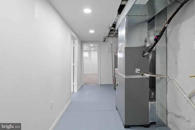 hallway with finished concrete flooring, heating unit, baseboards, and recessed lighting