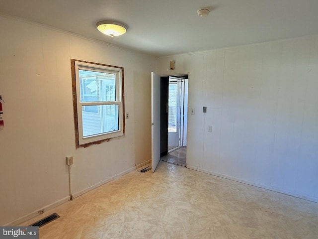 unfurnished room with visible vents, ornamental molding, light floors, and baseboards