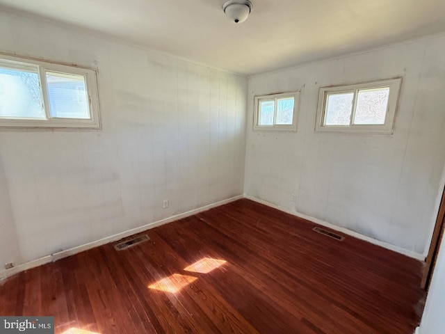 unfurnished room featuring visible vents, baseboards, and wood finished floors