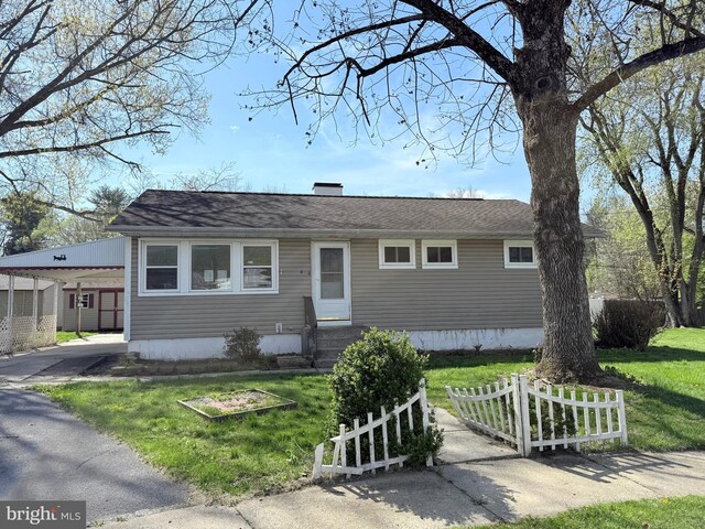 view of front of property featuring entry steps, fence, an attached carport, and a front lawn