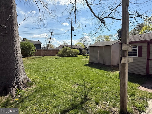 view of yard featuring a storage shed, fence, and an outbuilding