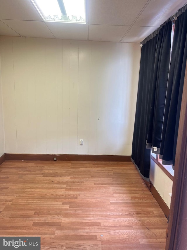 empty room with a paneled ceiling and light wood finished floors