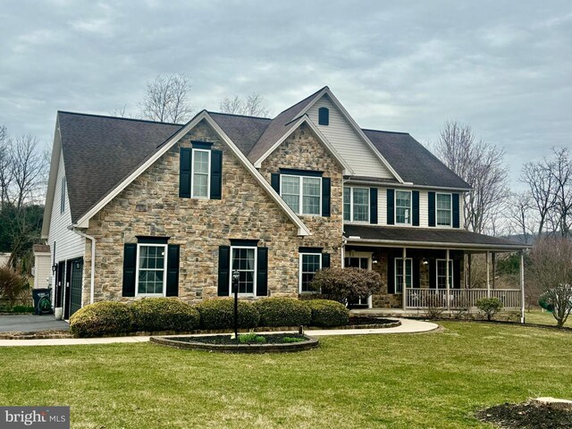view of front of house with stone siding, covered porch, and a front yard
