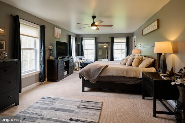 bedroom featuring light colored carpet, baseboards, and a ceiling fan