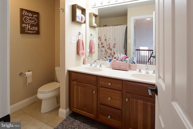 bathroom with tile patterned floors, toilet, double vanity, and baseboards