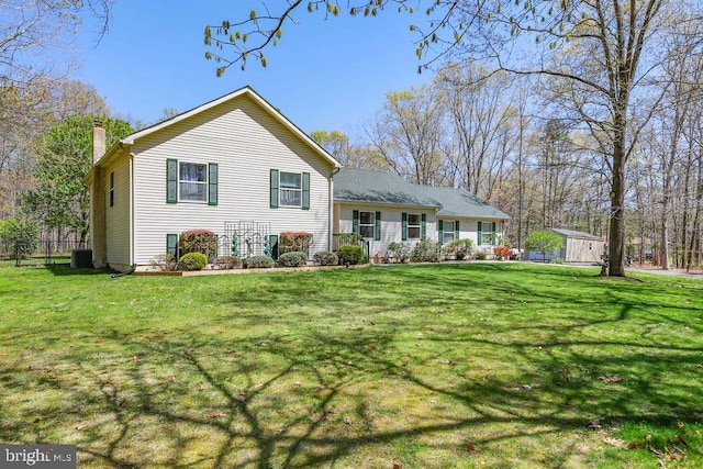 view of front of house with a chimney, central AC, and a front yard