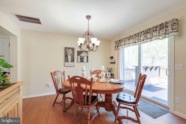dining space with baseboards, light wood-type flooring, a chandelier, and visible vents