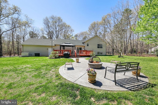 back of house with a gazebo, a deck, a patio area, a yard, and a fire pit