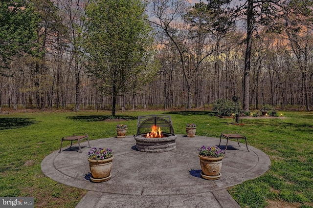 view of patio featuring a view of trees and a fire pit