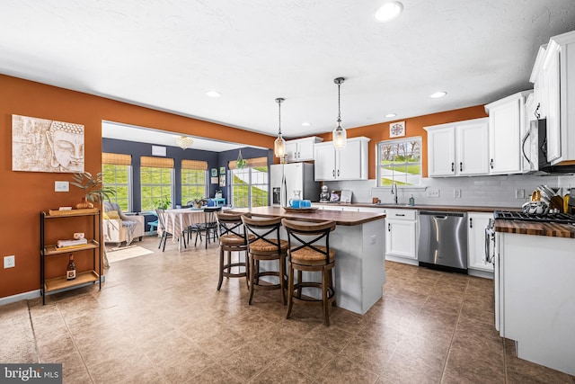 kitchen featuring stainless steel appliances, a kitchen breakfast bar, a kitchen island, and butcher block counters