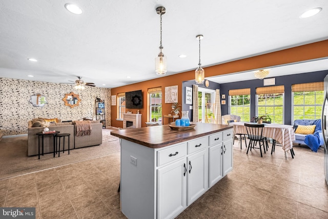 kitchen featuring wooden counters, open floor plan, pendant lighting, white cabinetry, and recessed lighting