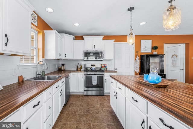 kitchen featuring white cabinets, stainless steel appliances, a sink, and wooden counters