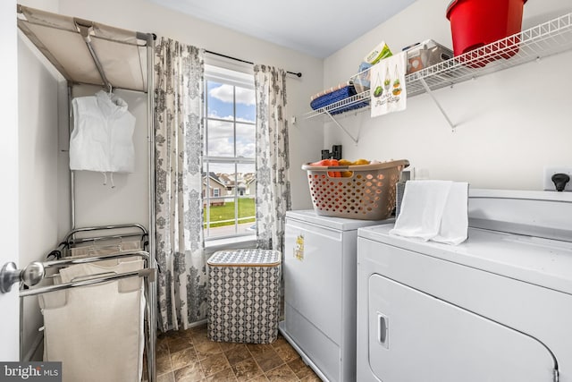 laundry room with stone finish flooring, washing machine and clothes dryer, laundry area, and plenty of natural light