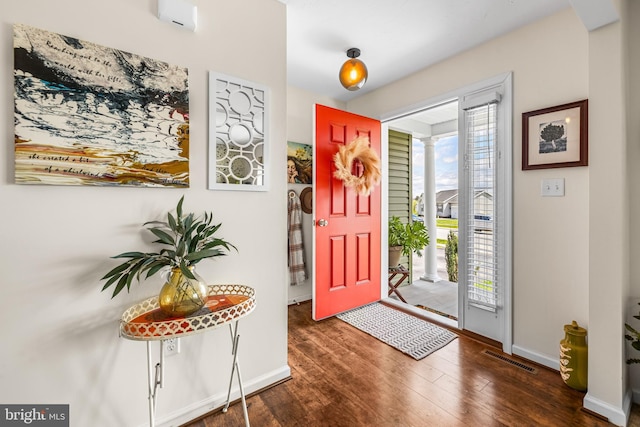 entryway featuring arched walkways, baseboards, wood finished floors, and visible vents