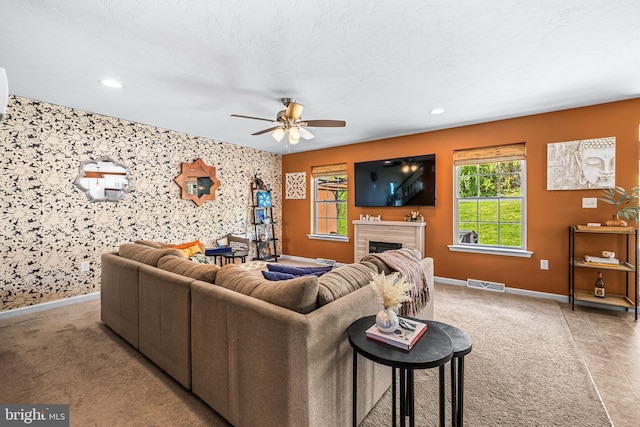 carpeted living room featuring wallpapered walls, visible vents, and baseboards