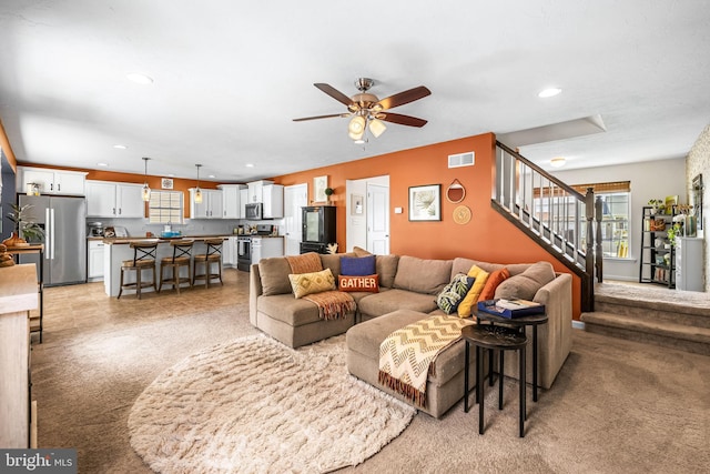 living room with stairway, a ceiling fan, light carpet, visible vents, and recessed lighting