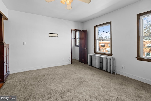 empty room featuring carpet, baseboards, radiator, and ceiling fan