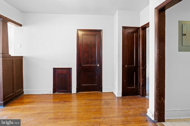 spare room with light wood-style flooring, baseboards, and electric panel