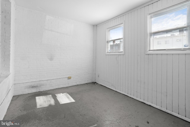 unfurnished room featuring brick wall and concrete flooring