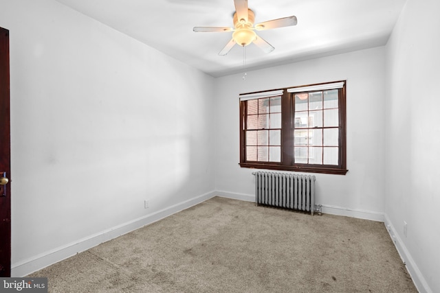 spare room with radiator heating unit, carpet, baseboards, and a ceiling fan