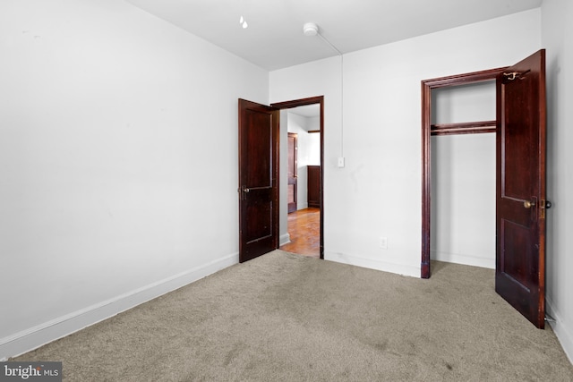 unfurnished bedroom with a closet, carpet, and baseboards