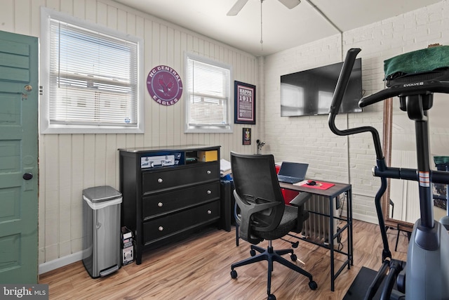 home office with brick wall, a ceiling fan, and wood finished floors