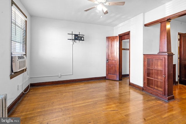 empty room with ornate columns, wood finished floors, and ceiling fan
