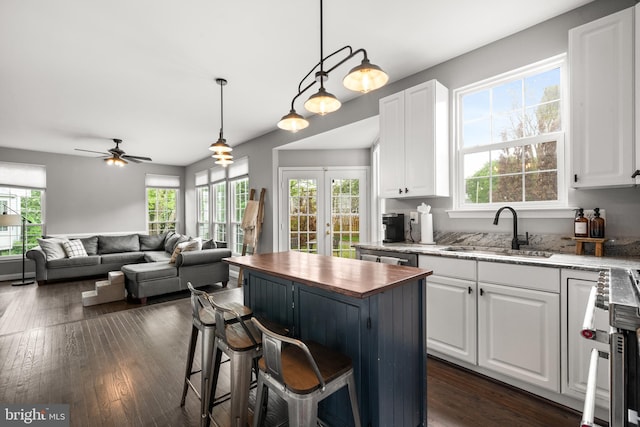 kitchen featuring butcher block countertops, a sink, plenty of natural light, and white cabinets