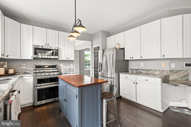 kitchen featuring appliances with stainless steel finishes, butcher block counters, and white cabinetry
