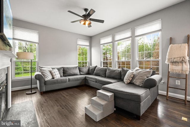 living area with baseboards, ceiling fan, dark wood-style floors, and a premium fireplace