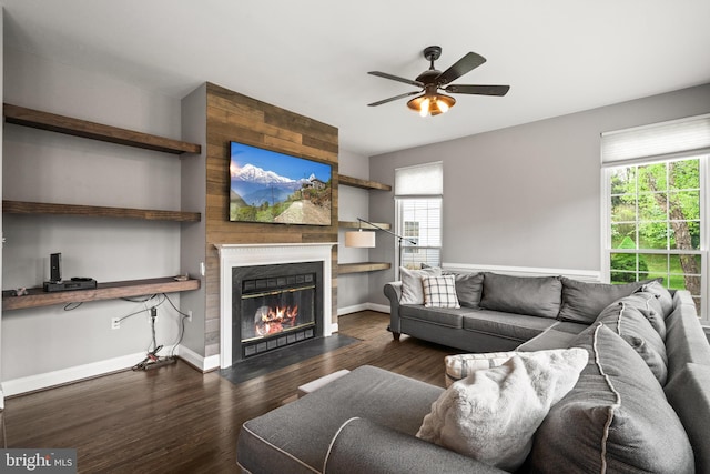 living area with a fireplace with flush hearth, ceiling fan, wood finished floors, and a wealth of natural light