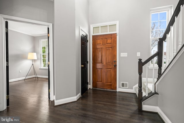 foyer featuring visible vents, crown molding, stairway, baseboards, and dark wood-type flooring