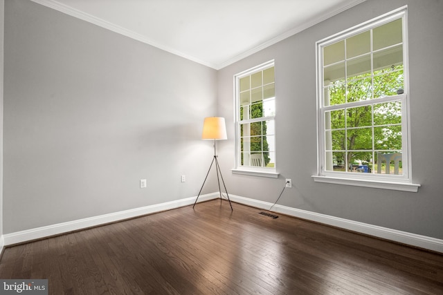 unfurnished room featuring wood-type flooring, baseboards, visible vents, and ornamental molding