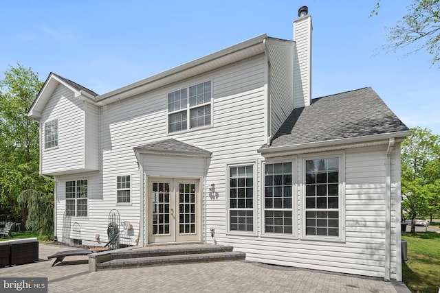 back of property with french doors, a shingled roof, a patio area, and a chimney