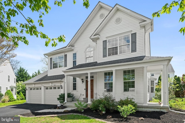 traditional-style home featuring a garage, aphalt driveway, covered porch, and a shingled roof
