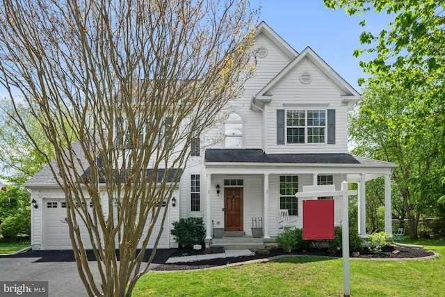 view of front of home featuring a porch, an attached garage, aphalt driveway, and a front lawn