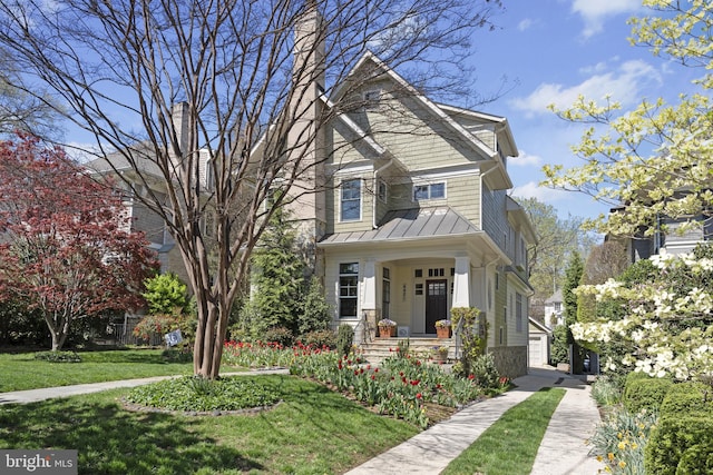 craftsman-style home with a chimney, a standing seam roof, a front lawn, and metal roof