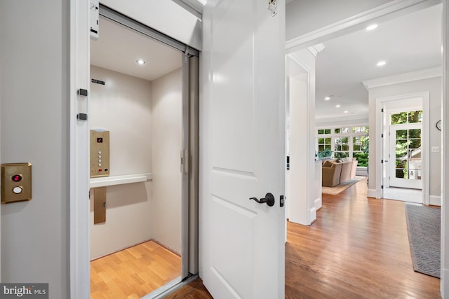 interior space with crown molding, recessed lighting, elevator, and wood finished floors