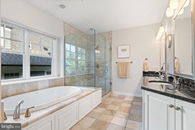 full bath with baseboards, double vanity, a stall shower, a garden tub, and a sink