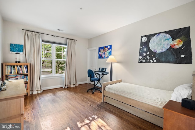 bedroom with visible vents, baseboards, and wood finished floors