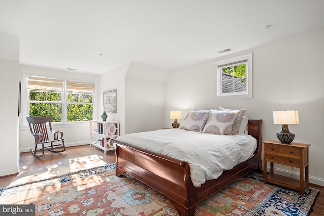 bedroom featuring visible vents, baseboards, and wood finished floors