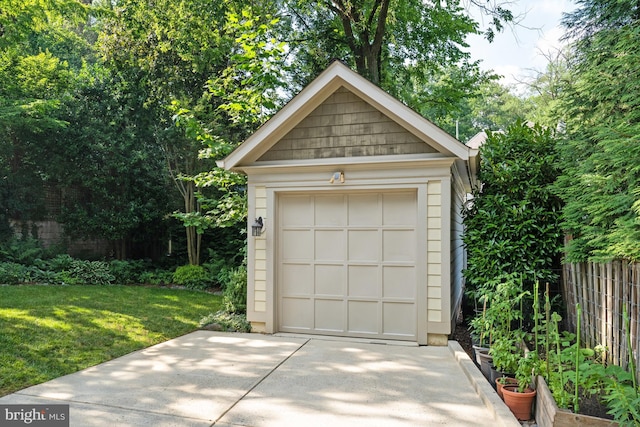 detached garage featuring concrete driveway and fence