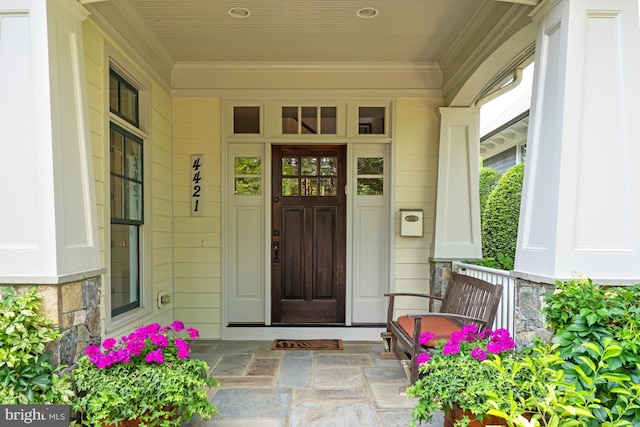 entrance to property featuring a porch and stone siding