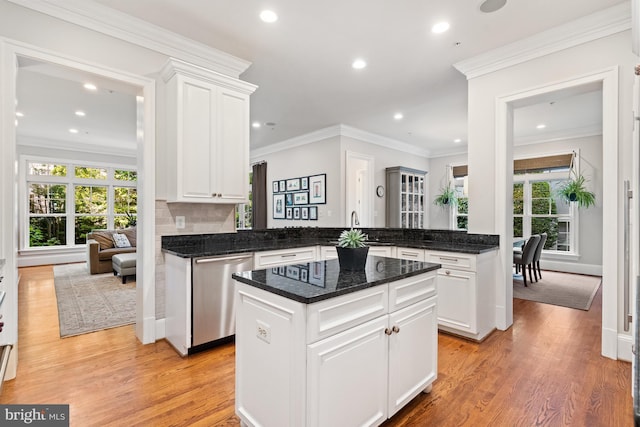 kitchen featuring light wood-style flooring, ornamental molding, a kitchen island, dishwasher, and plenty of natural light
