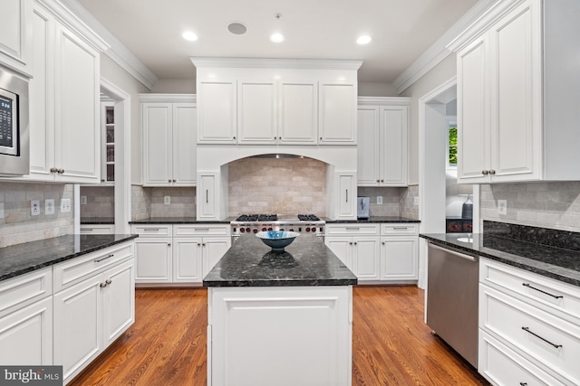 kitchen featuring light wood-type flooring, appliances with stainless steel finishes, white cabinetry, and dark stone countertops