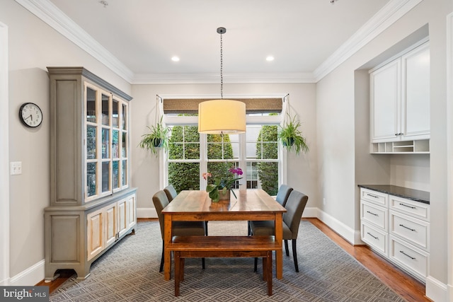 dining area featuring light wood finished floors, baseboards, and crown molding
