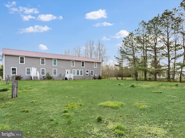 rear view of property featuring metal roof and a lawn
