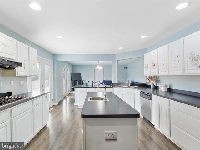 kitchen with dishwasher, a sink, dark countertops, under cabinet range hood, and gas cooktop